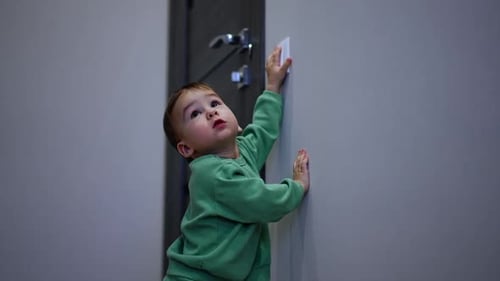 Toddler Reaches for Light Switch in Indoor Setting