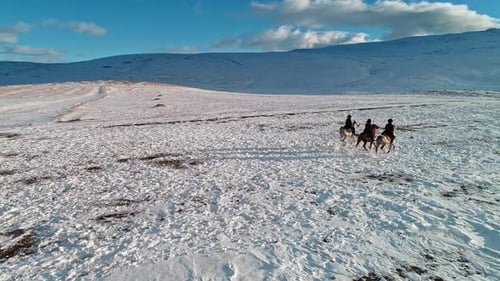 Riders on Horses Travel Across Snowy Landscape