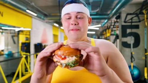 Man Holds Tempting Burger Inside Exercise Facility