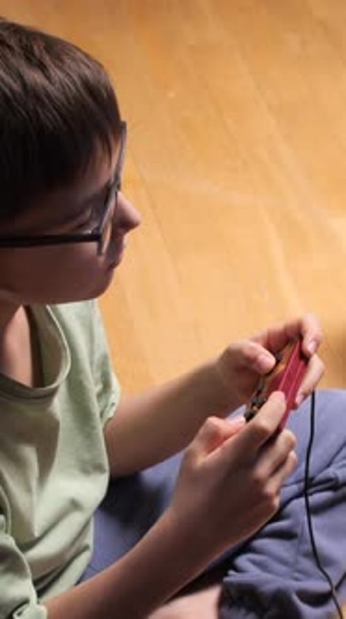 Child Plays Video Game on Handheld Console