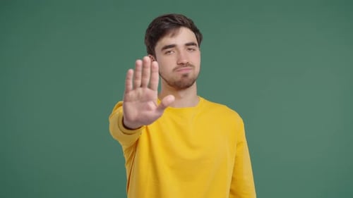 Portrait Of Serious Man In Yellow Outfit Showing Rejecting Gesture Stop Palm
