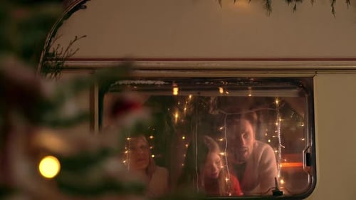 Cheerful Family Gazing Through RV Window at Christmas