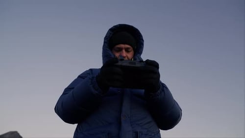 Man Adjusting Drone Controller on Mountain at Sunrise