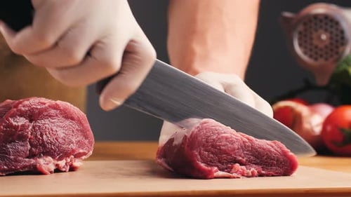 Raw Beef Being Cut on Cutting Board