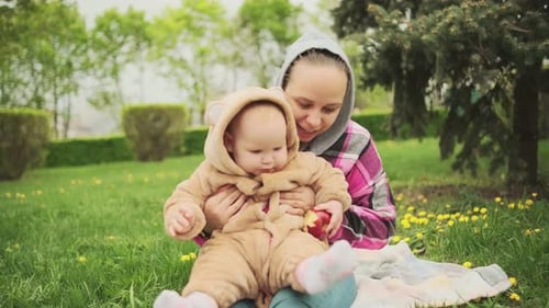 A Mother and Her Baby Enjoy a Beautiful Spring Day in the Park They are Sitting on a Blanket