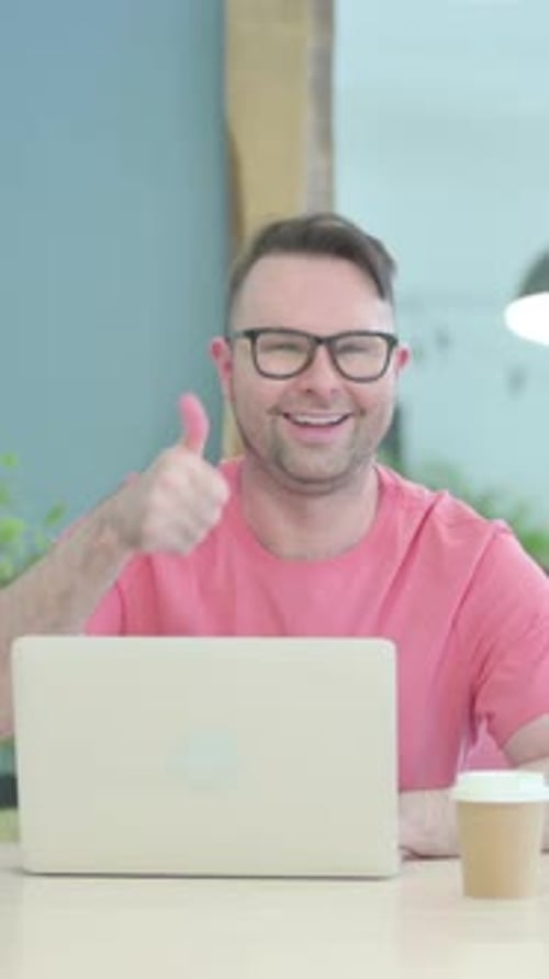 Man Gives a Thumbs Up Working on Laptop