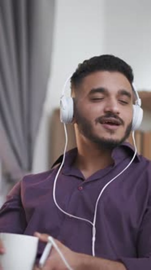 Man Listening to Music and Drinking from Mug