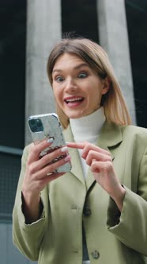 Excited woman celebrates mobile win in city