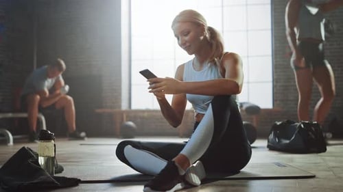 Woman Using Phone While Sitting in Gym