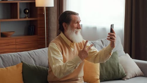 Senior Man Video Calling on Mobile Phone at Home