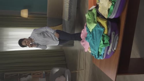 Vertical Video of a Brunette Middleaged Woman Having a Call on the Background While Packing a