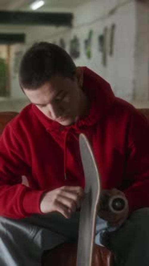 Young Adult Repairing Skateboard in Urban Workshop