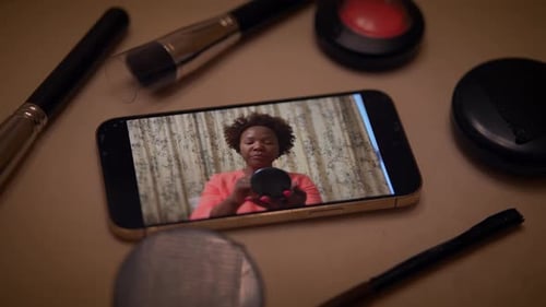 Woman Applying Makeup on Phone with Cosmetics Around