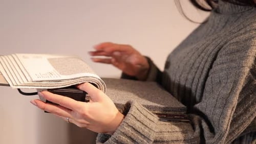 Woman Inspects Fabric Swatches in Design Book