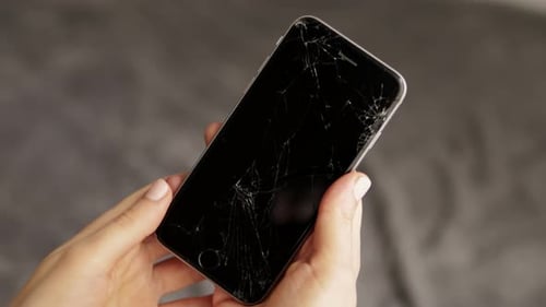 Hands Holding Cell Phone with Cracked Screen