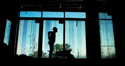 Man, injury or back pain on construction site for building, fatigue or wheelbarrow in silhouette
