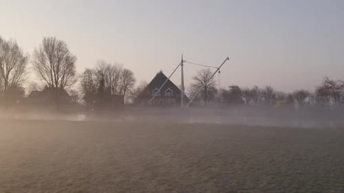 Aerial view of traditional farmhouse at dutch countryside with fog, Netherlands