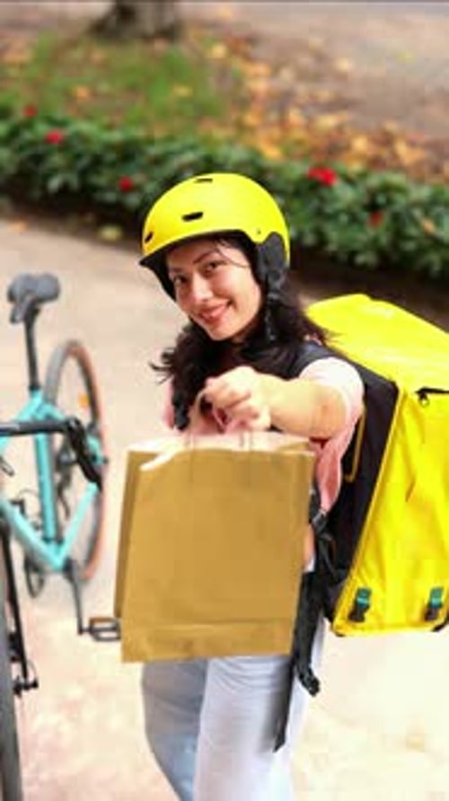 vertical Asian delivery woman giving a paper bag to a client