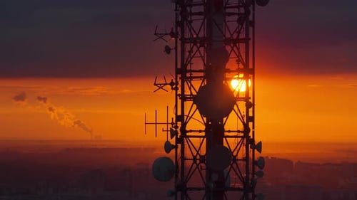 Aerial drone view of a large telecommunications tower set against an intense orange sunset over Belg