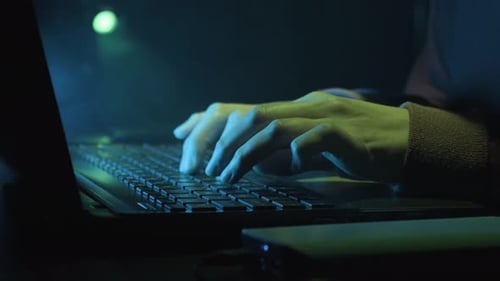 Hand Of A Hacker Typing On Keyboard Of Laptop Computer In His Office. - close up