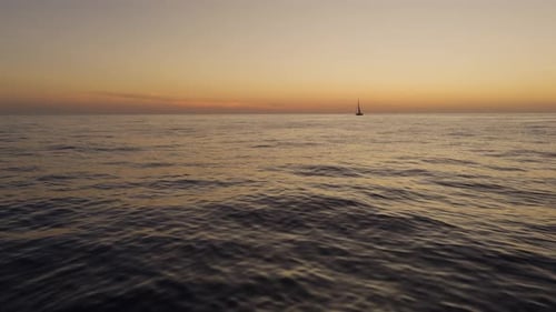 Sailboat On The Sea During A Beautiful Sunset With Warm, Golden, And Orange Gradient Sky. - aerial