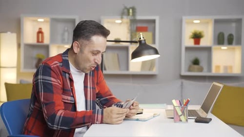 Excited Man Counts and Throws Money at Desk