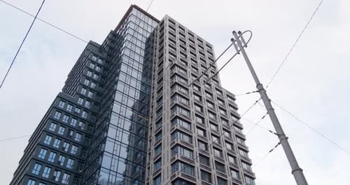 Skyscraper against cloudy sky, low angle view. Camera panning left