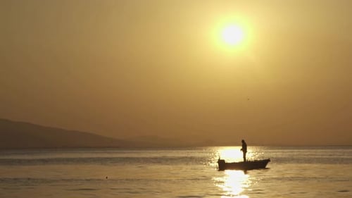Lone Silhouette on Boat at Sunrise at Sea
