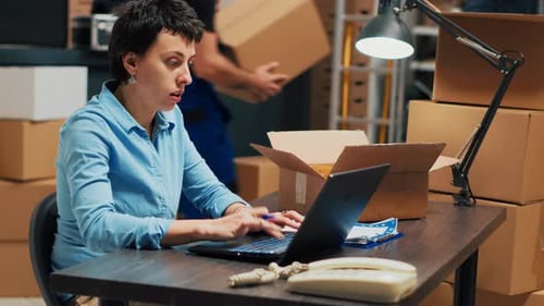 Woman Works at Desk in Shipping Warehouse