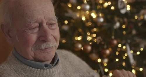 Senior Man Holding Christmas Gift Looking Emotional
