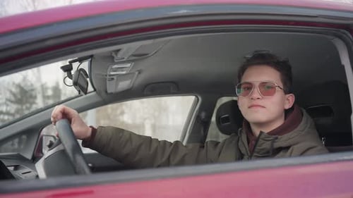 Teen in Car Smiles Holding Steering Wheel