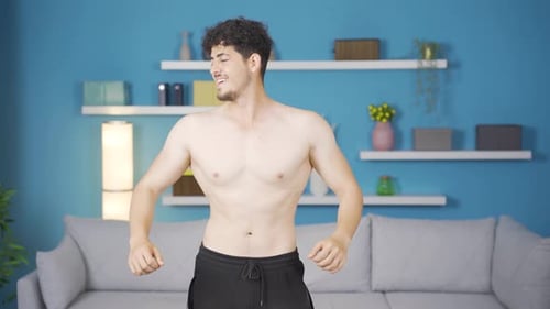 Shirtless Man Flexing Biceps in Home Gym