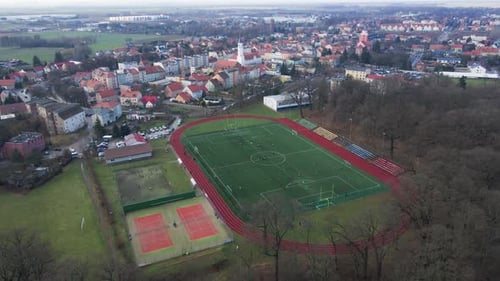 Aerial view of stadium in small town, Players play football on soccer field
