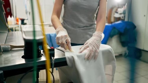 Woman Inspecting White Shirt in Industrial Laundry