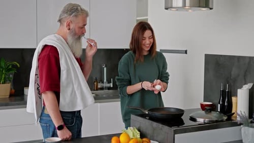 Un hombre mayor con cabello gris y barba exuberante con una camiseta roja Pinceles sus dientes mientras es moreno