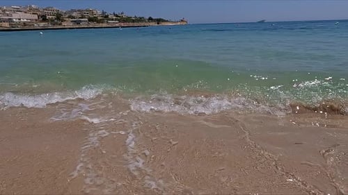 Ascending close up of a gorgeous beach with blue sea water while the waves break towards the camera