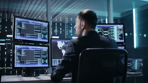 Vista posterior del controlador/operador técnico trabajando en su estación de trabajo con varias pantallas. Posts