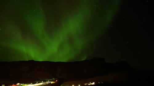 Scenic View Of Aurora Borealis Flickering At Night Over Silhouette Mountains In The Northern Hemisph