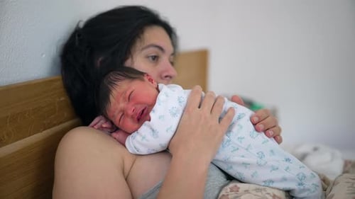 Mother Holding Newborn Baby in Home Interior
