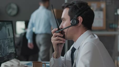 Man Monitors Security Cameras and Uses Walkie-Talkie