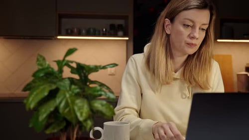 Mulher trabalhando em casa no local de trabalho à noite usando laptop