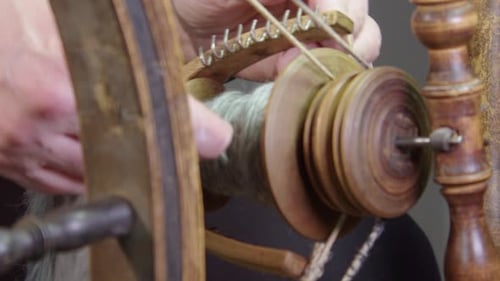 Slo mo closeup detail: Artisan hands with wool yarn on spinning wheel
