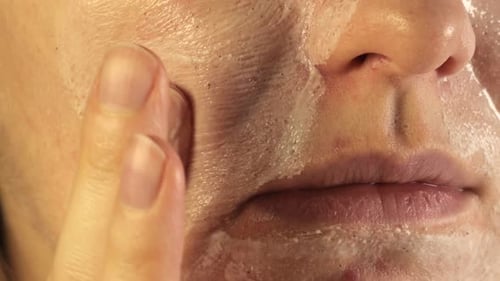 Woman Applies Exfoliating Scrub to Face in Close Up