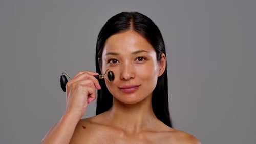 Woman Using Facial Roller for Skin Care