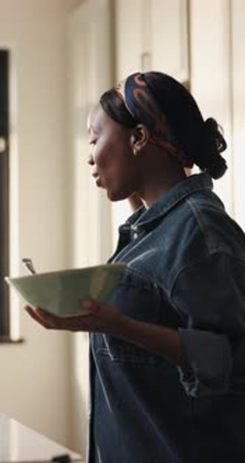 Woman with Bowl Dancing in Kitchen at Home