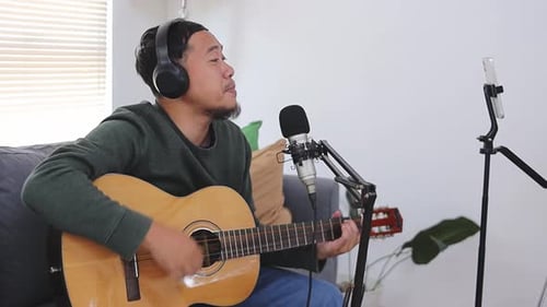 Young Adult Singing and Playing Guitar Indoors