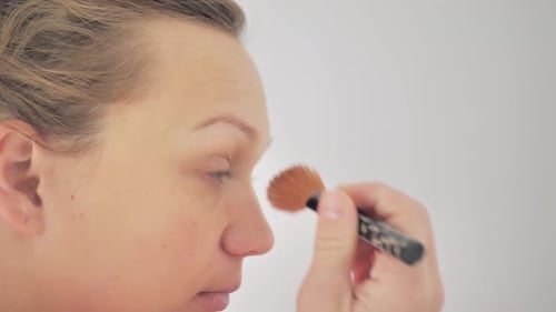 Woman Applying Makeup on Her Face with Brush