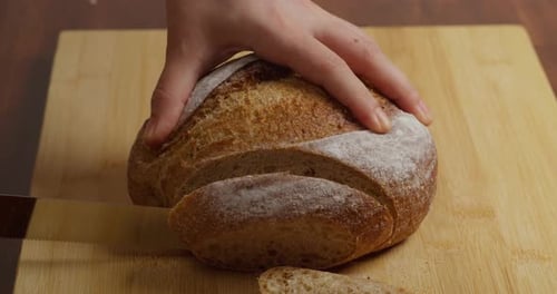 Nahaufnahme des Schneidens von knusprigem Mehrkorn-Sauerteigbrot in einer Hausküche bei der Zubereitung von frischem Toast für