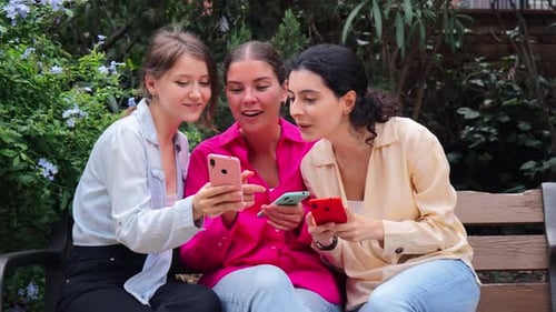 Friends Laughing Looking at Phone on Park Bench