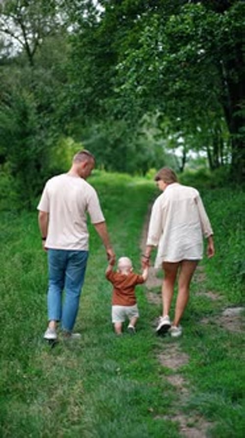 Rear view of a Caucasian couple with their little baby on the walk.